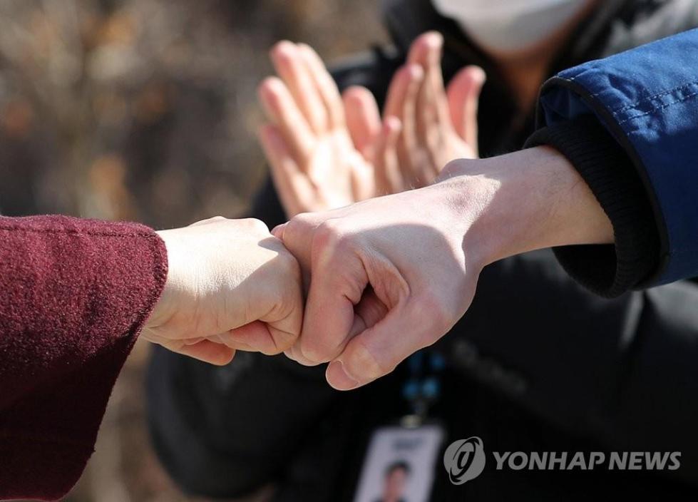 韩国治愈并解除隔离的新冠患者在离开生活治疗中心前与医务人员击拳