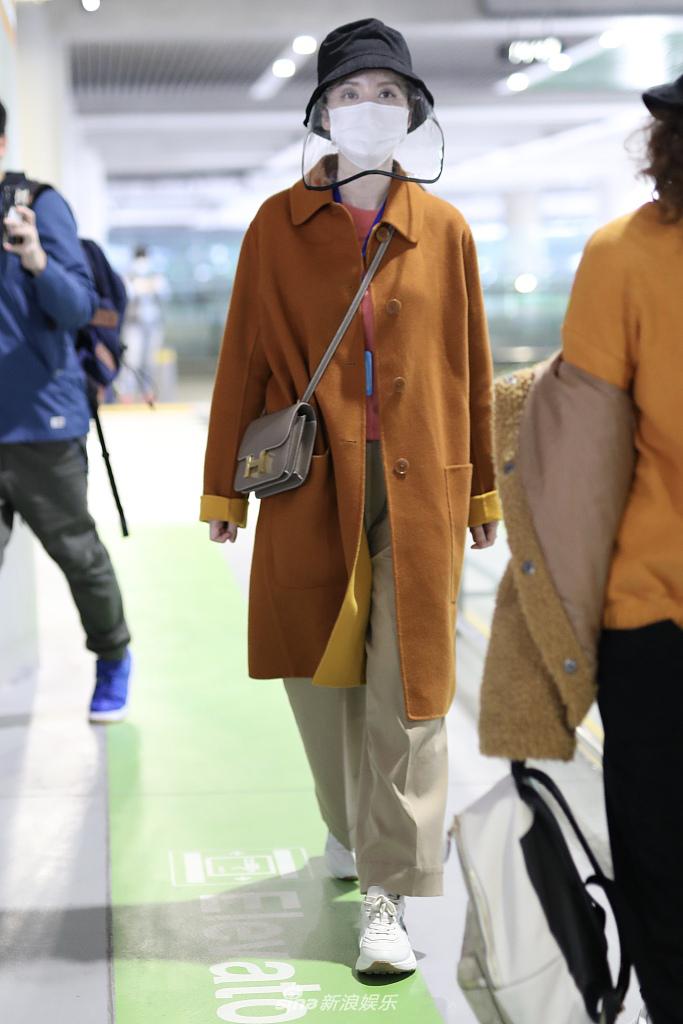 张萌穿黄色大衣现身机场 热情打招呼心情靓