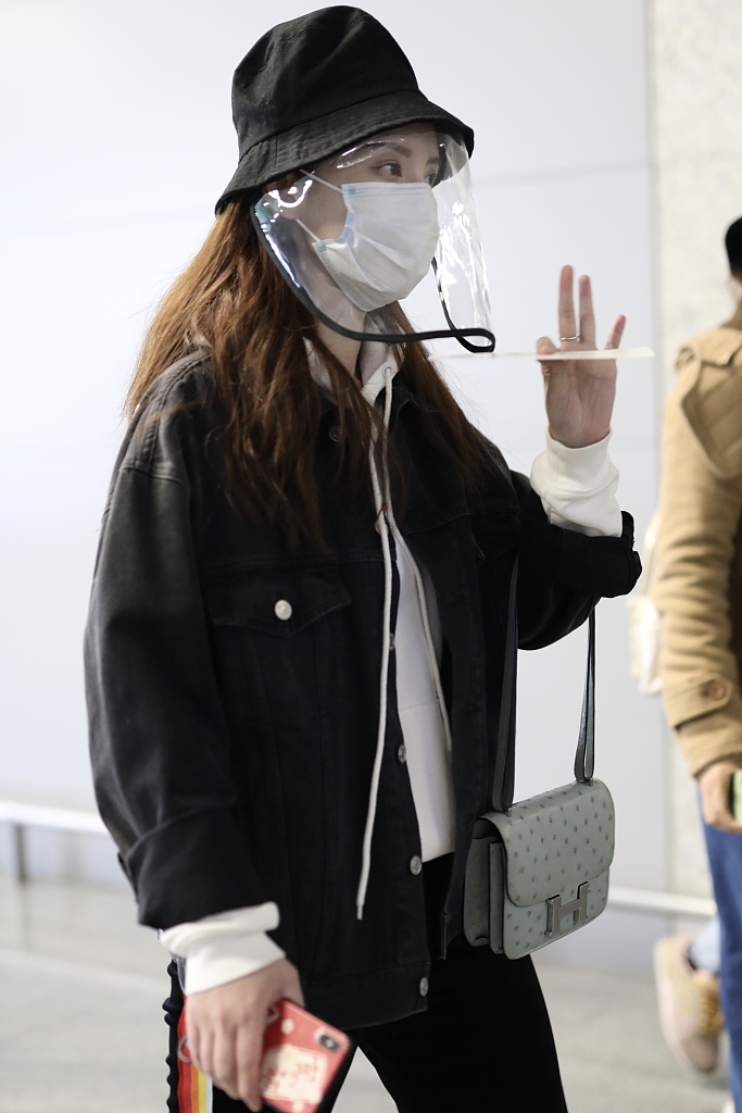 张萌戴黑色渔夫帽现身机场 猫咪手机壳暴露少女心