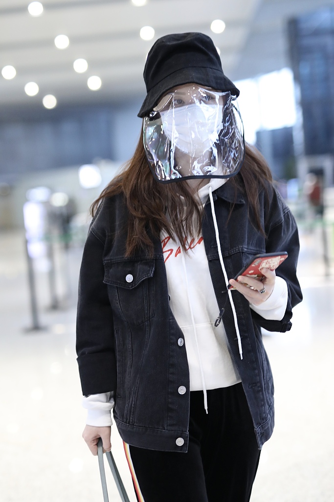 张萌戴黑色渔夫帽现身机场 猫咪手机壳暴露少女心