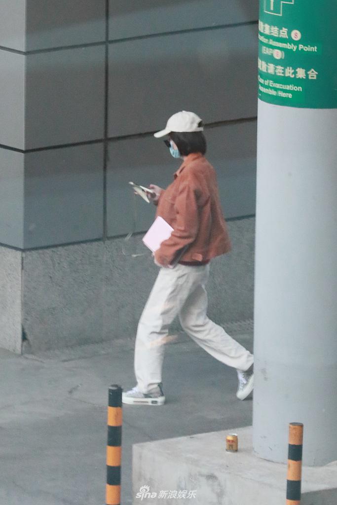 张雪迎穿橘色外套现身机场 一路低头玩手机十分悠闲