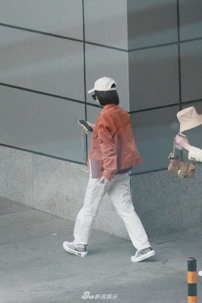 张雪迎穿橘色外套现身机场 一路低头玩手机十分悠闲