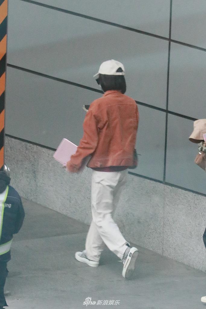 张雪迎穿橘色外套现身机场 一路低头玩手机十分悠闲