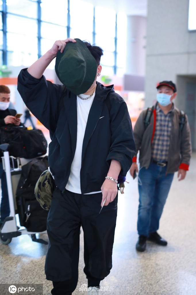 钱枫穿一身黑衣现身机场 高举帽子遮脸防止被拍