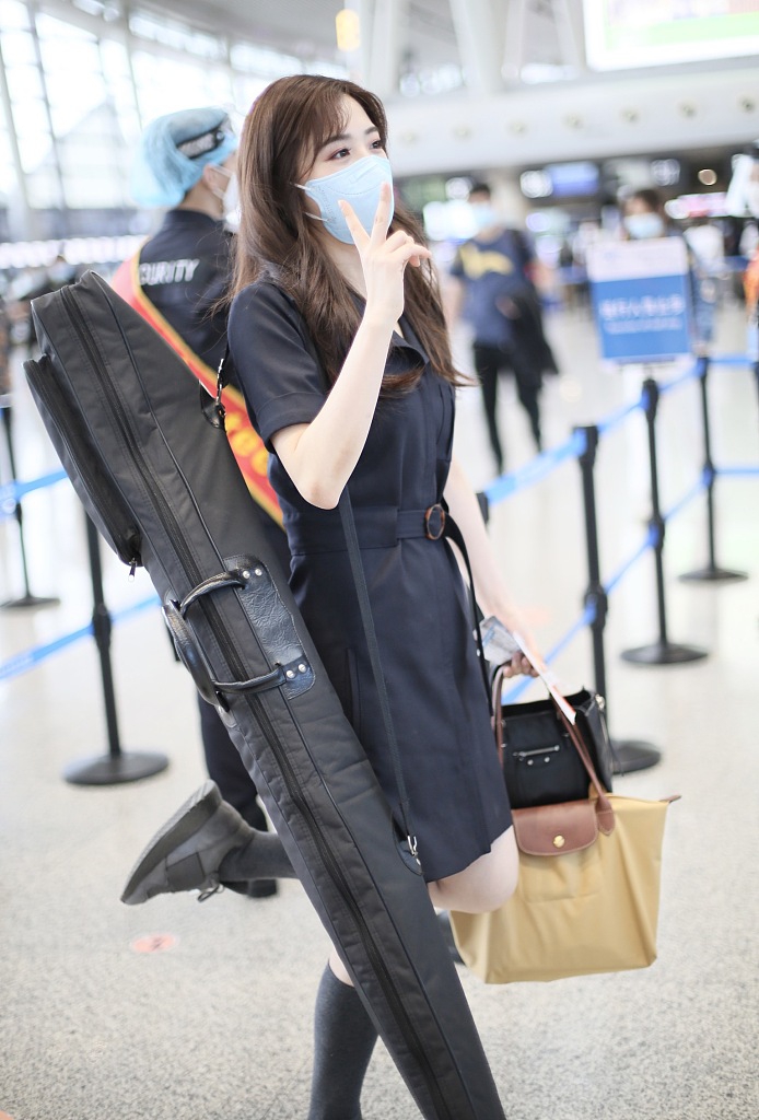 张含韵背乐器现身机场 穿黑色连衣裙少女感十足