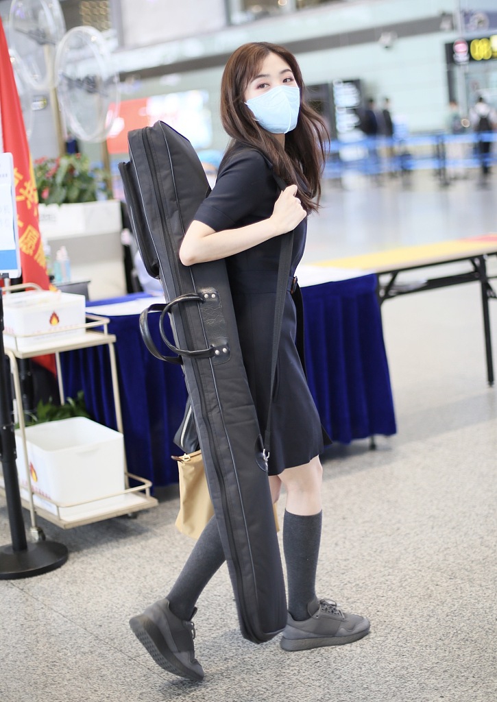 张含韵背乐器现身机场 穿黑色连衣裙少女感十足
