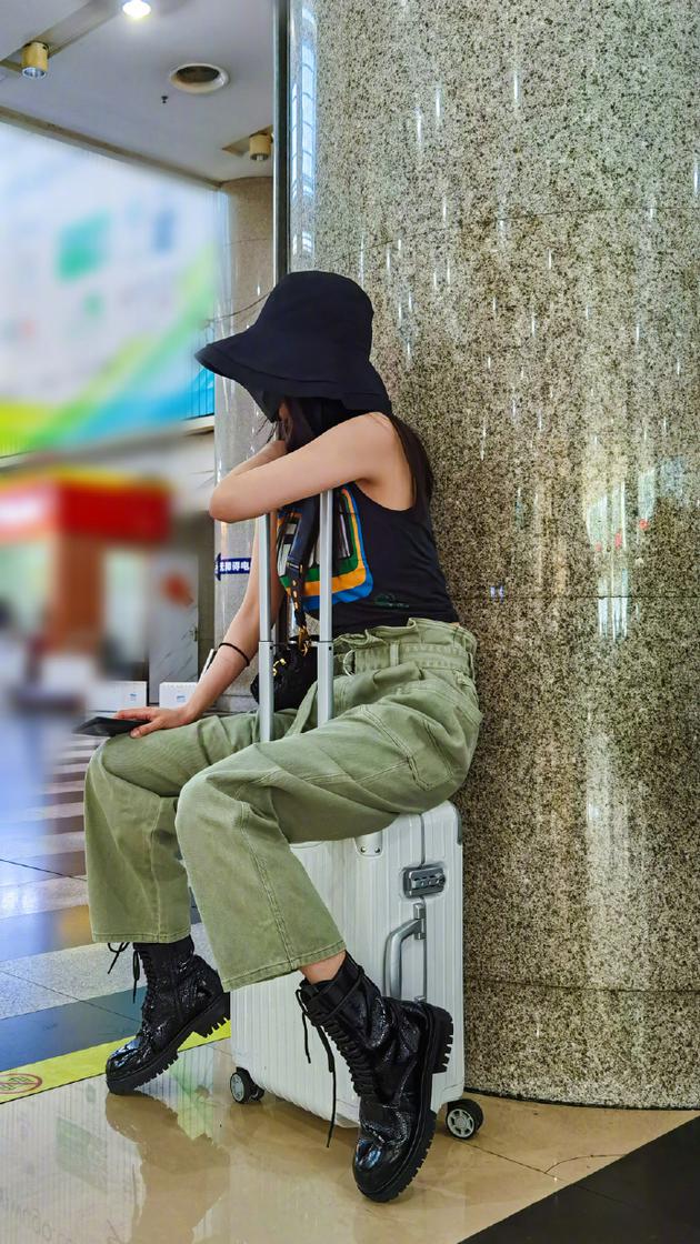 杨幂穿无袖背心搭工装裤潮范足 坐行李箱上眼神无辜