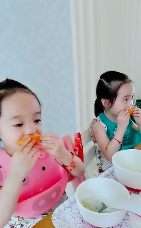 杨云晒双胞胎女儿吃橙子 欢欢乐乐戴围兜表情呆萌