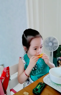 杨云晒双胞胎女儿吃橙子 欢欢乐乐戴围兜表情呆萌