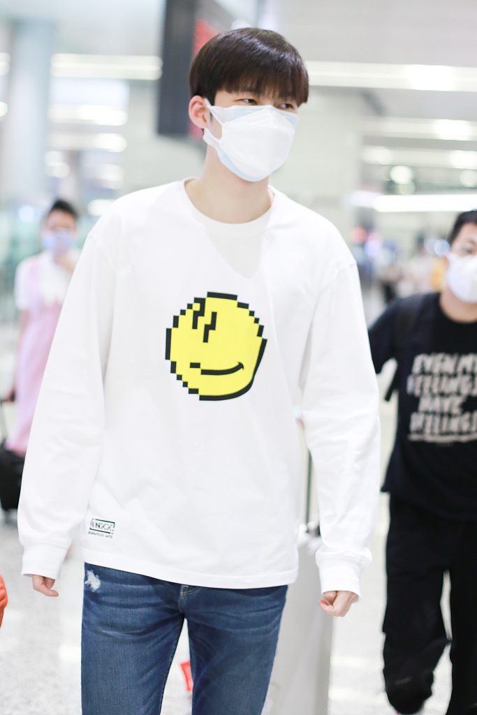 董力穿白色笑脸T恤走机场 表情认真身高引人瞩目