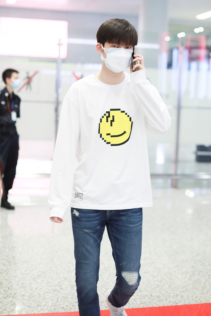 董力穿白色笑脸T恤走机场 表情认真身高引人瞩目