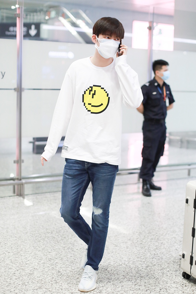 董力穿白色笑脸T恤走机场 表情认真身高引人瞩目