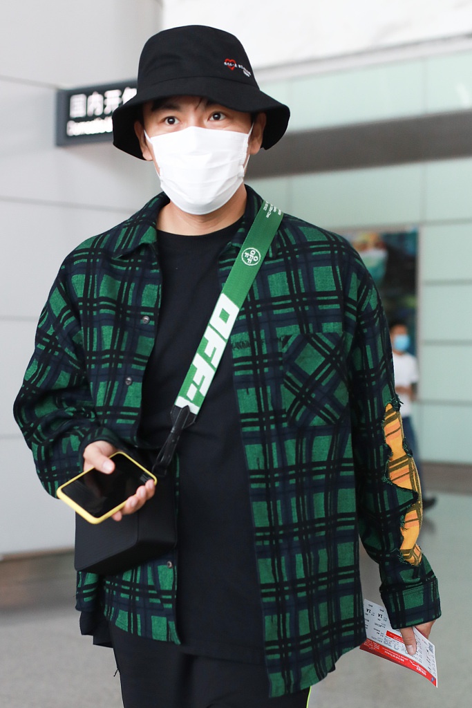 秦昊装扮休闲现身机场 “一起爬山么”手机壳抢镜