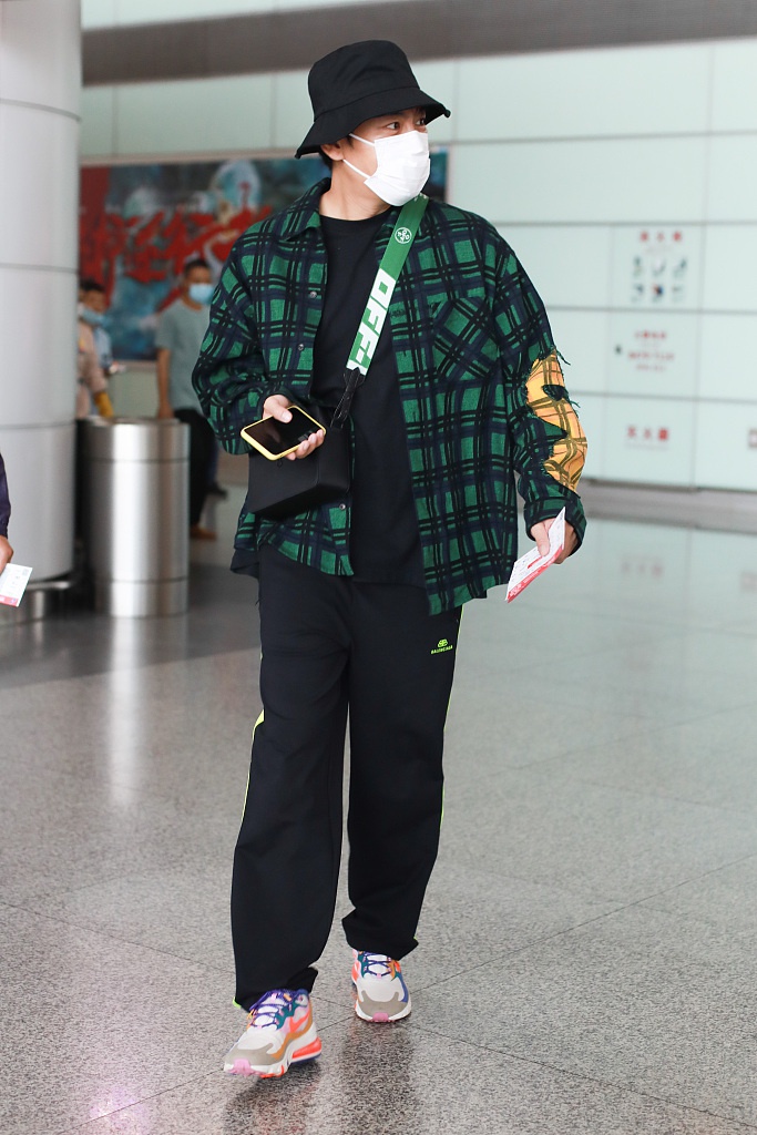 秦昊装扮休闲现身机场 “一起爬山么”手机壳抢镜