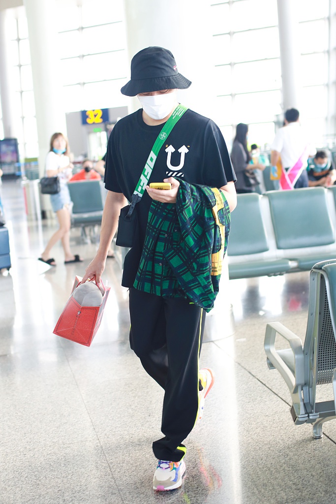 秦昊装扮休闲现身机场 “一起爬山么”手机壳抢镜