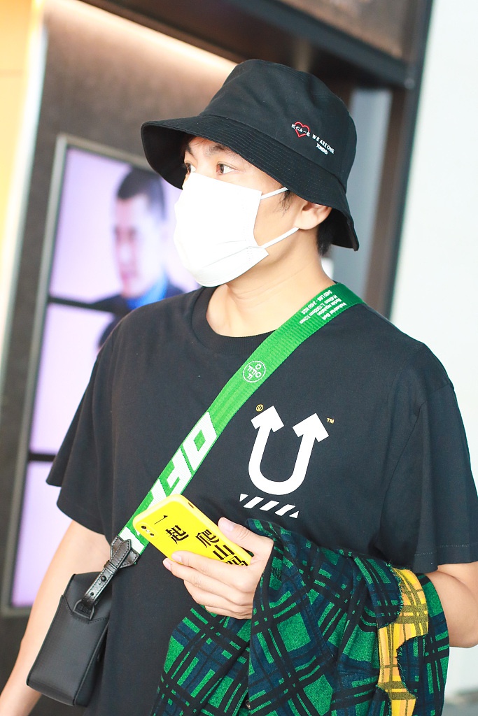 秦昊装扮休闲现身机场 “一起爬山么”手机壳抢镜