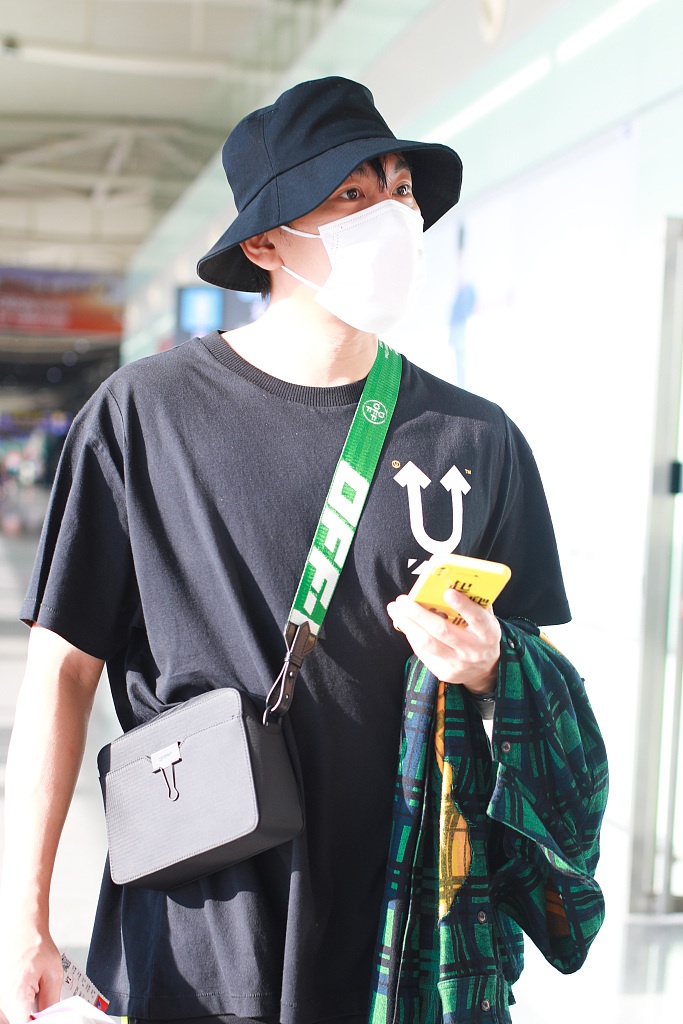秦昊装扮休闲现身机场 “一起爬山么”手机壳抢镜
