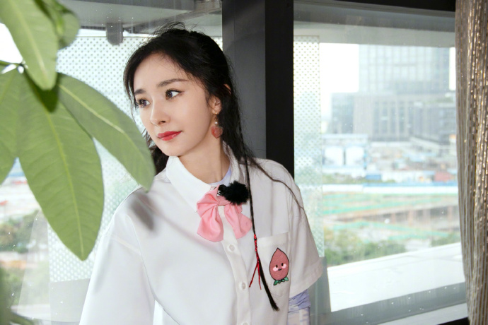 杨幂梳双马尾戴粉色领结 对镜比剪刀手少女感满满