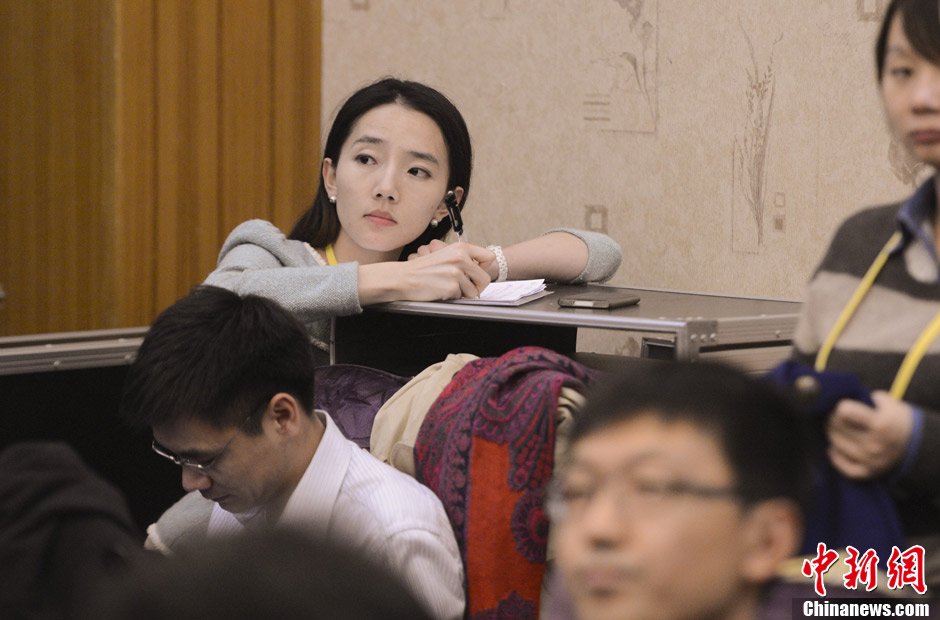 11月11日,一名女记者在十八大新闻中心采访室内记录代表发言.