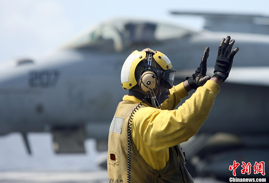 图为2007年9月7日,美国航母地勤人员给飞行员发出信号.