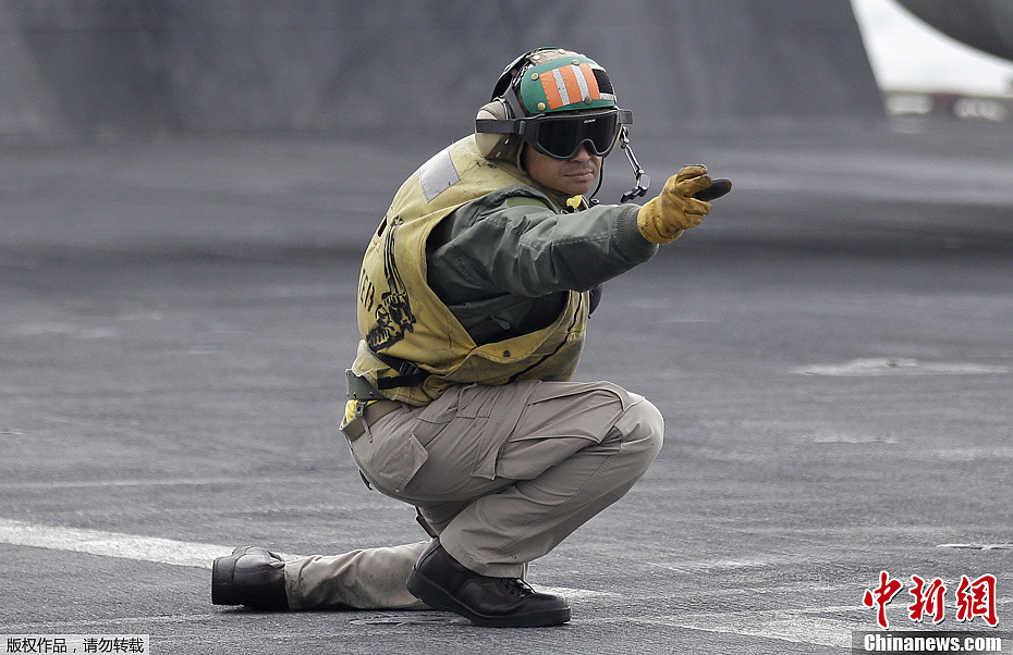 2012年2月13日,美国"林肯"号航母地勤人员给飞机起飞信号.