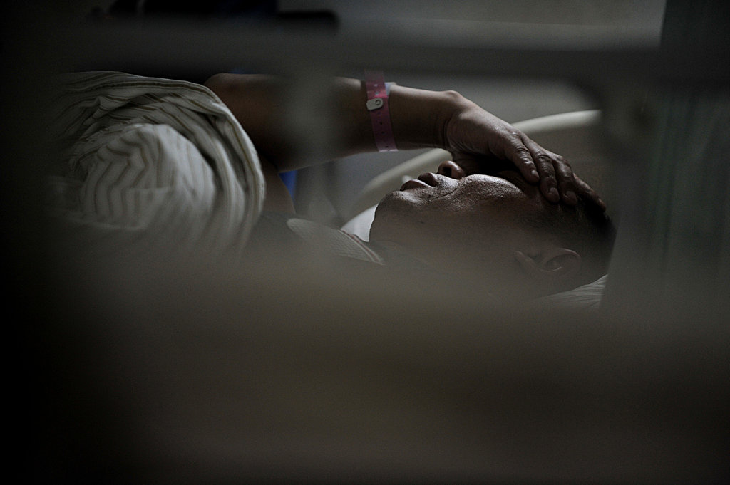 被殴打致腰椎骨折躺在病床上,他不停地用手捂住脸遮住自己痛苦的表情