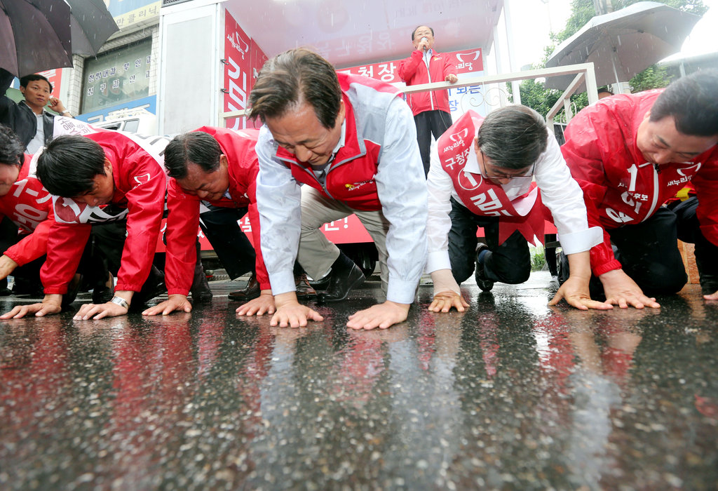 韩国首尔市长候选人冒雨跪地拉票