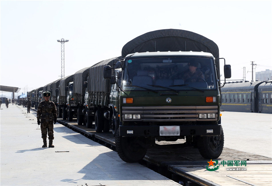 载有装甲装备的军列缓缓开进货运场站. 轮式车辆依次驶下火车平板.