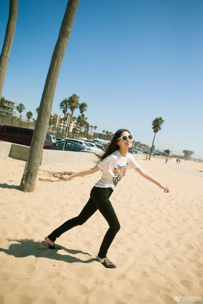 倪妮赤脚漫步沙滩笑容满面