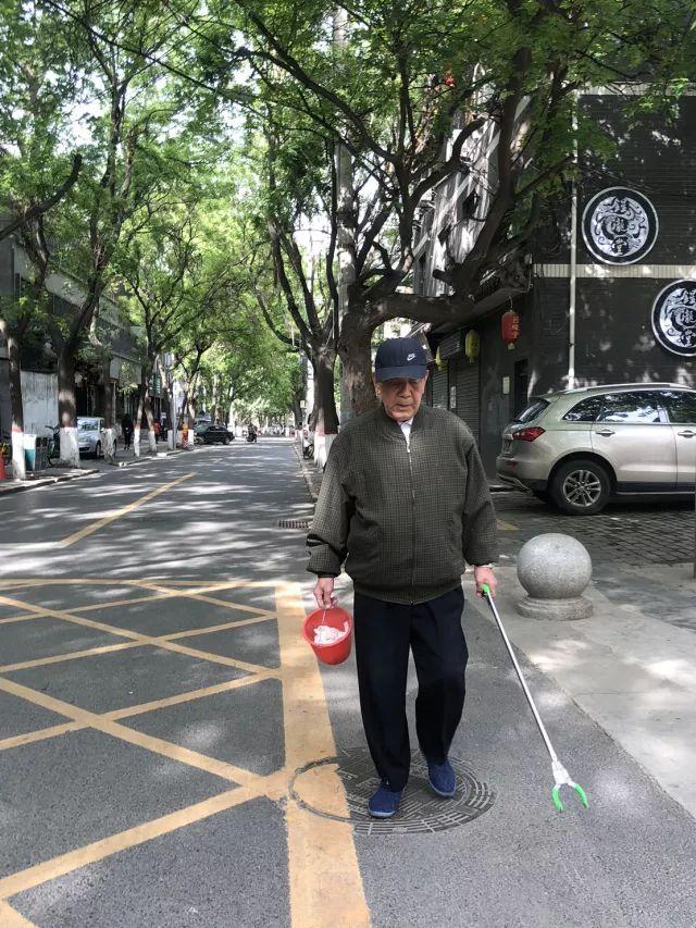 曾老爷子,一手提着红色塑料桶,一手拿着垃圾夹,不顾头顶烈日,循着以往