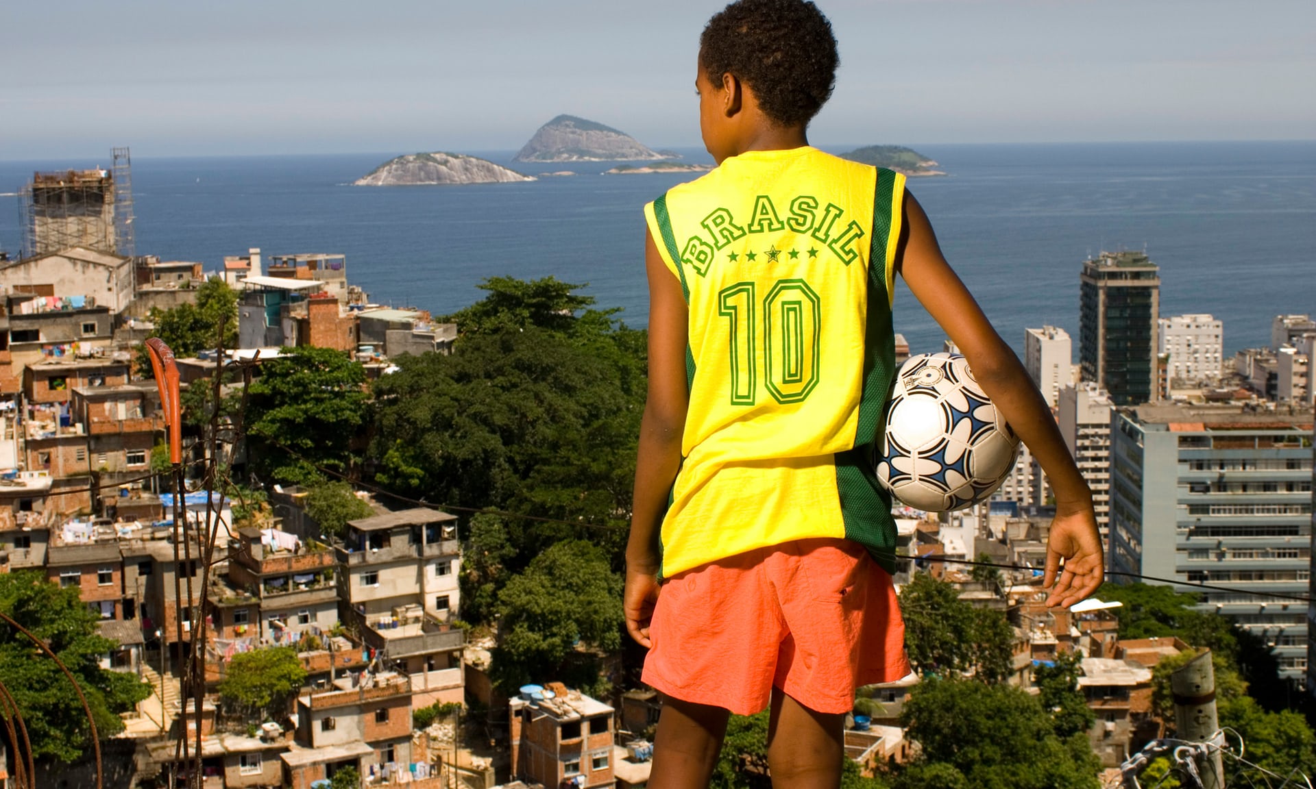 一位男孩带着足球站在巴西里约热内卢的一处贫民窟前.