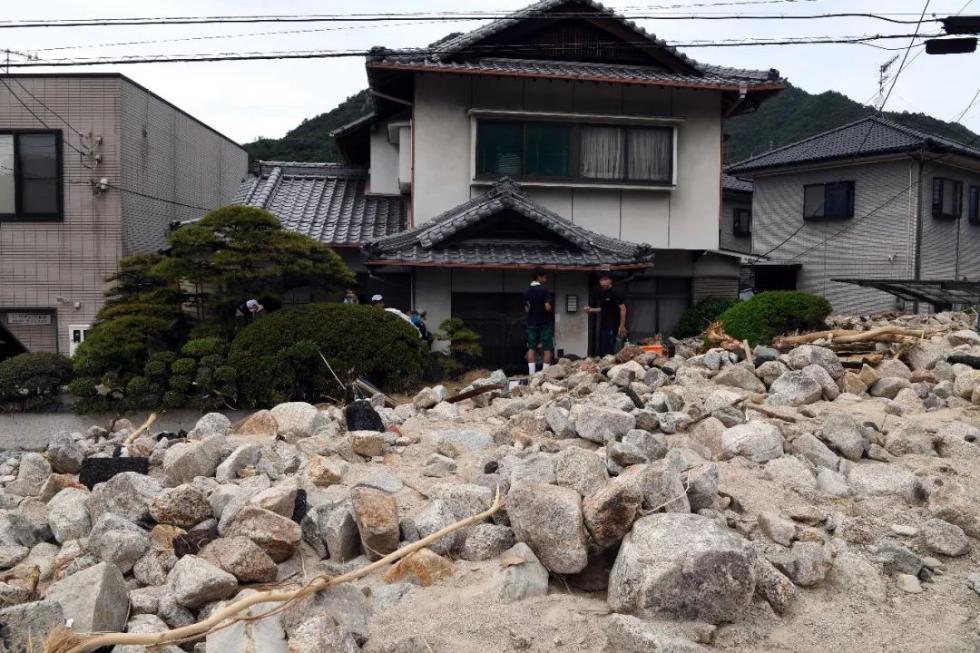 7月11日，在日本广岛吴市天应町地区，居民清理房屋外的泥沙。新华社记者马平摄