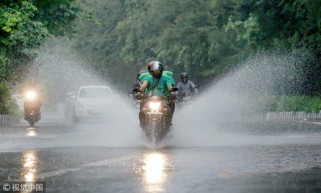 9 印度新德里降暴雨引发市区洪涝 市民骑车出行如冲浪