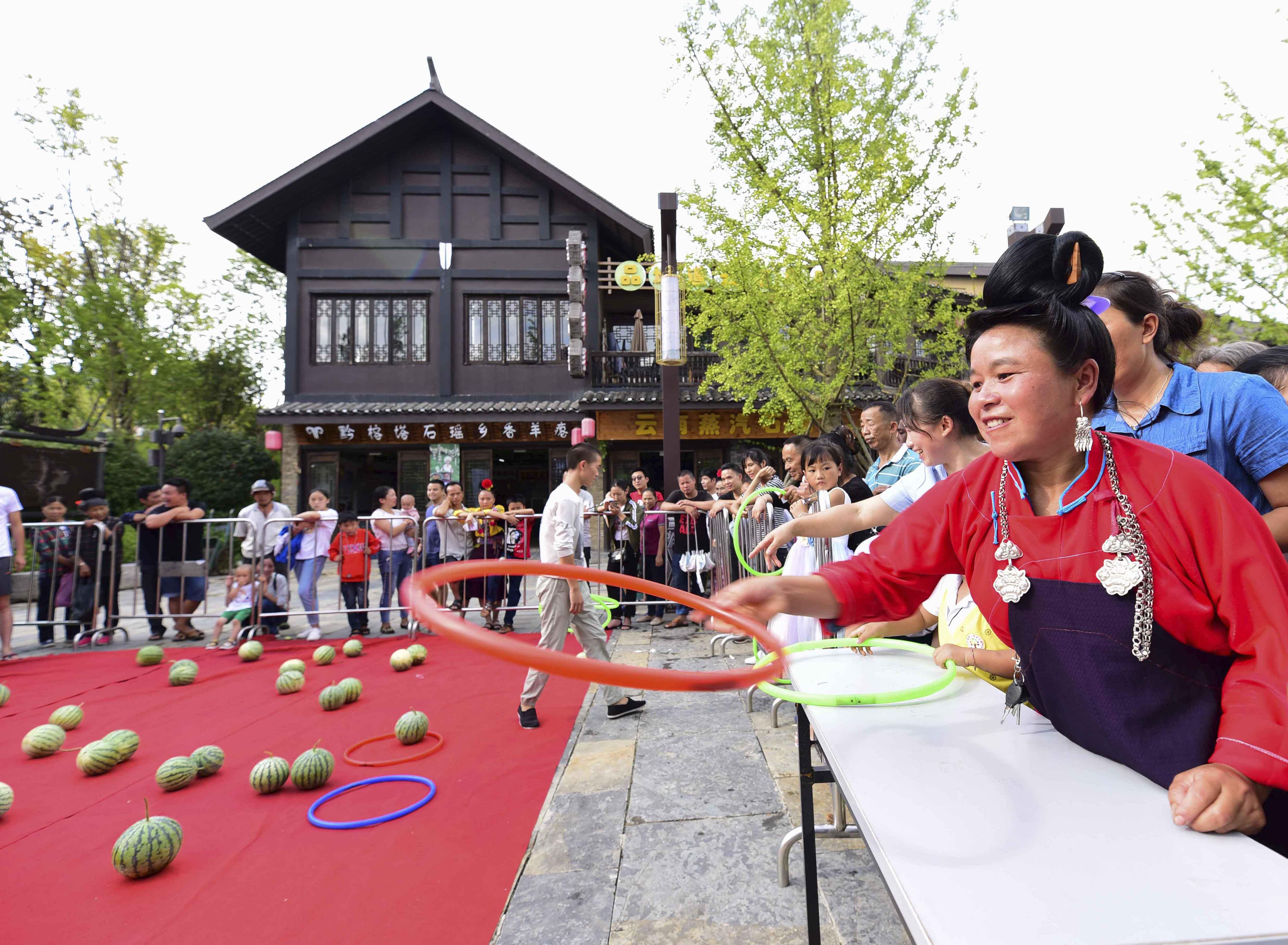人们在贵州省丹寨县万达小镇趣味西瓜节活动现场参加"套西瓜"游戏.