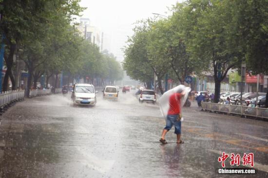一名男子用塑料薄膜挡雨，在雨中奔跑。 朱柳融 摄