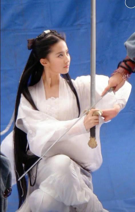 刘亦菲在和对手“比试”剑法，在空空的蓝幕下，没有打光，但是这颜依旧能打！