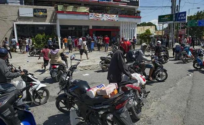 许多灾民骑着摩托车聚集到商铺门前。(图：法新社)