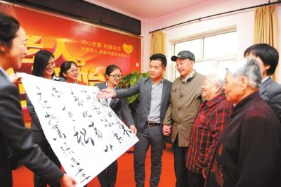 广汇物业米东分公司副总经理常磊(左五)为敬老院老人带去工作人员写的节日祝福语