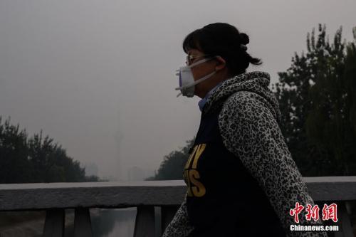 10月15日，北京一名市民戴防霾口罩在户外行走。中新社记者 崔楠 摄