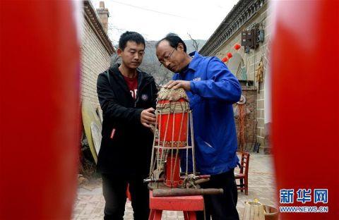 王永军（右）在指导儿子王涛给安塞腰鼓蒙皮（10月19日摄）。 新华社记者刘潇摄