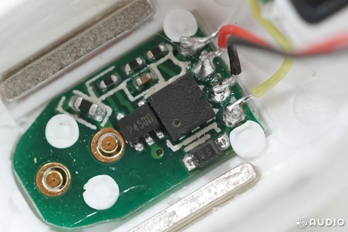 位于耳机内侧的充电触点小板特写，旁边有两块辅助定位的磁铁。