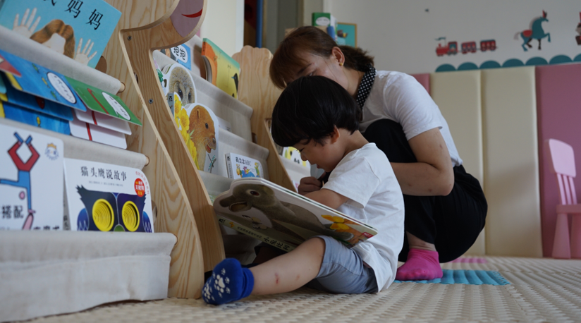 (图说: 宁陕县城南养育中心，一位年轻的母亲正在陪孩子读绘本)
