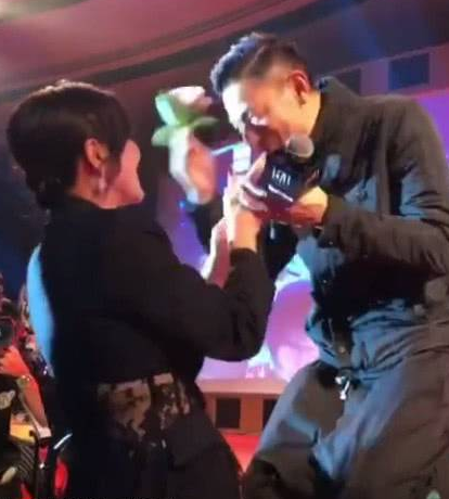 刘嘉玲递上鲜花，刘德华在舞台上跪下来，用头迎接嘉玲的礼物。