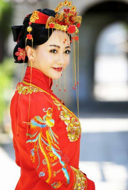 《情定三生》中的顾知夏，身穿大红色婚服，胳膊上还绣着凤凰的图案。凤冠简约美丽，回眸一笑百媚生。