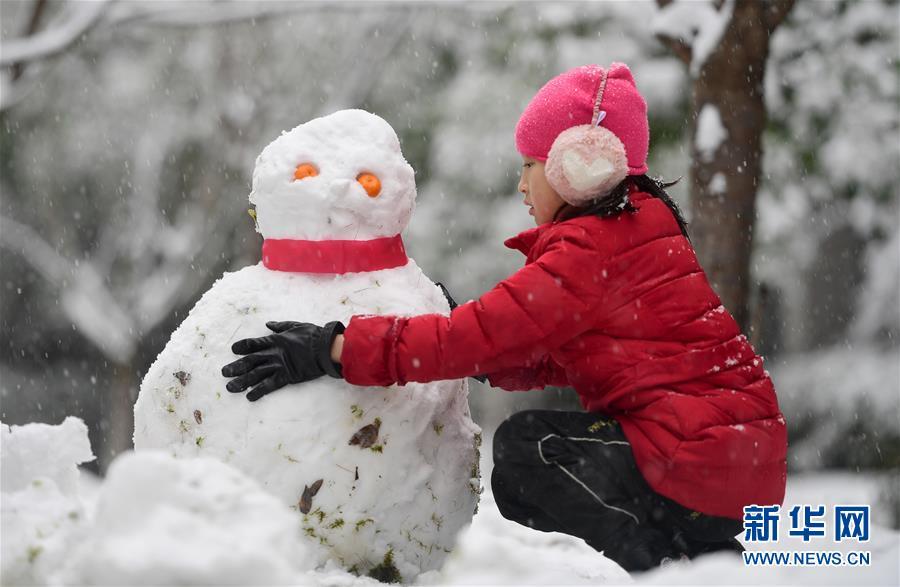 12月30日,在湖南长沙浏阳市城区,一名女孩在雪中堆雪人