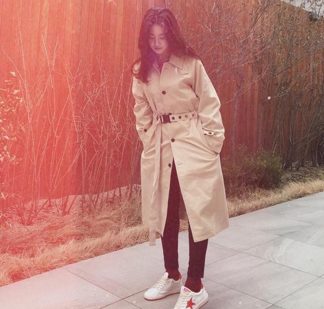卡其色的长款风衣搭配黑色长裤既潇洒又不失随意感,小白鞋也增加了几分休闲的气息。