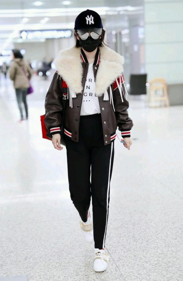 杨紫现身机场,戴着棒球帽搭配皮毛一体外套休闲又很酷,条纹运动裤配小白鞋轻松凹起造型。