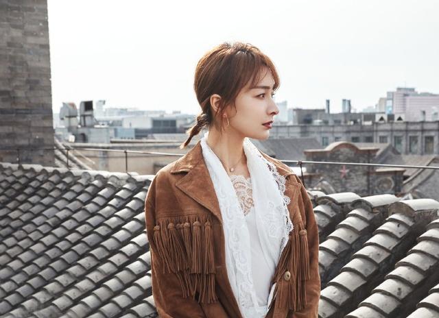 在一片砖瓦的屋顶，风衣搭配蕾丝衬衣的造型，有种浓浓的怀旧风。