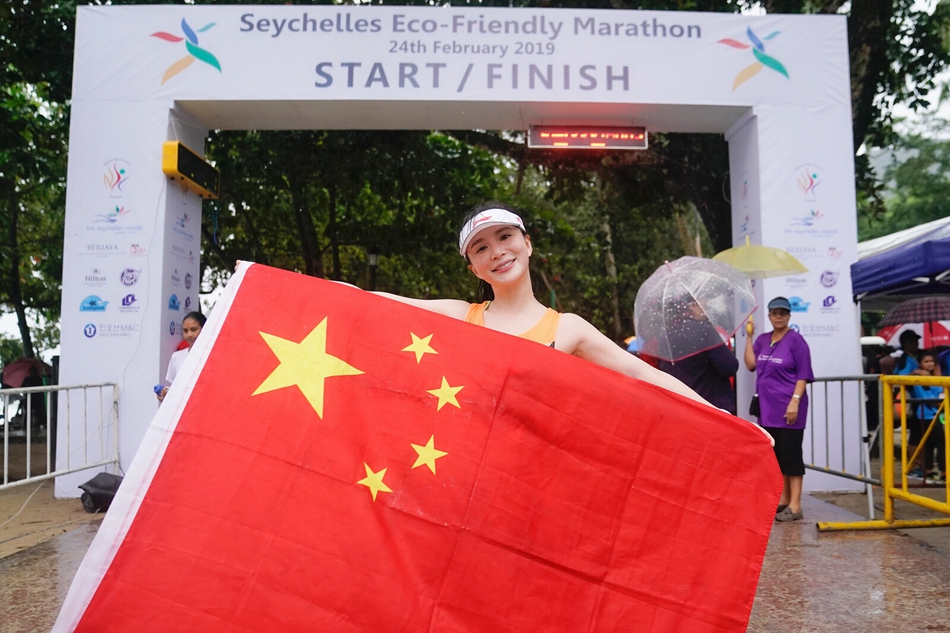 演员熊乃瑾在雨中跑完塞舌尔马拉松10k项目,跑过终点后,与五星红旗