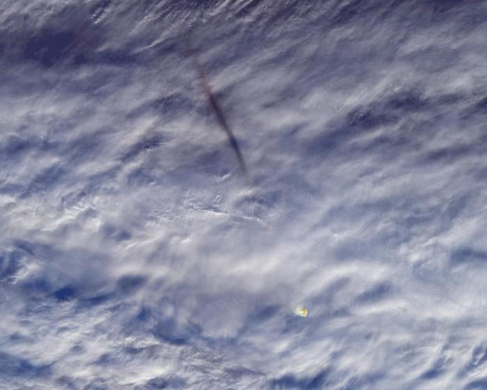 图像显示了流星在海上的烟雾路径，看起来像是穿过云层的黑色污迹。
